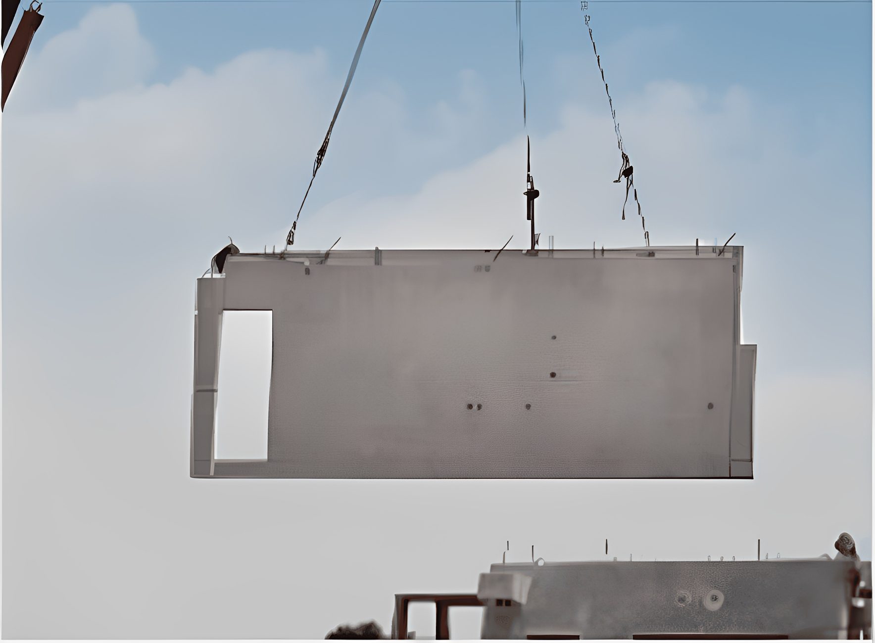 Concrete slab being lifted by crane cables.